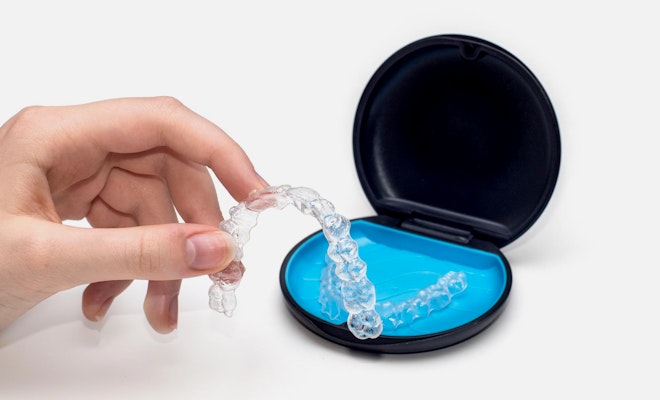 Person holding Invisalign in front of Invisalign container